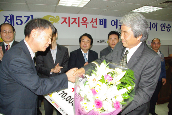 ▲지지옥션 강명주 회장(오른쪽)이 시니어팀 서봉수 9단에게 우승보드와 꽃다발을 전달하며 축하했다  